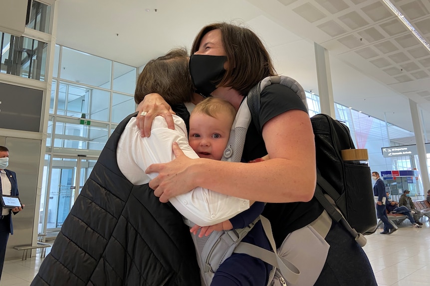 A group of people hug with a baby looking at the camera