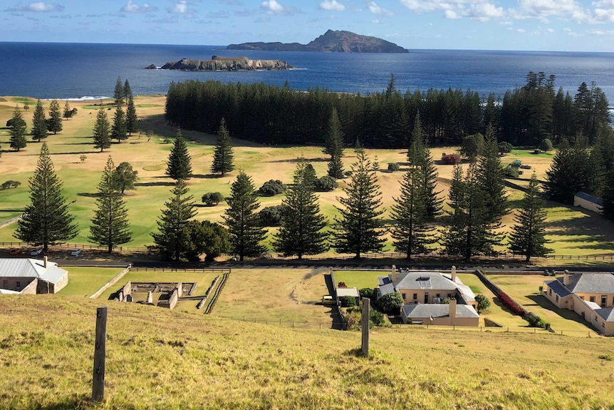 Norfolk Island looking out onto Phillip Island shows dry yellowing grass and old penal buildings