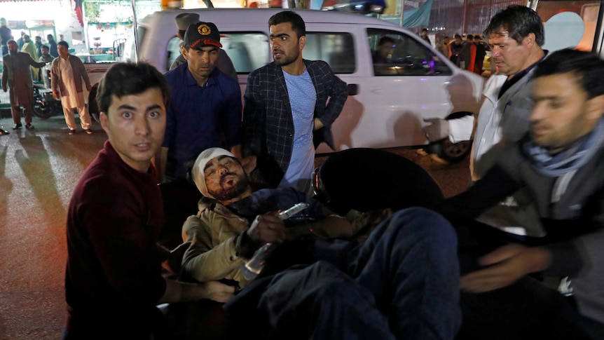 Afghan men carry an injured person to a hospital after a suicide attack in Kabul, Afghanistan.