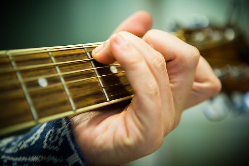 Close up on a hand strumming on a guitar.