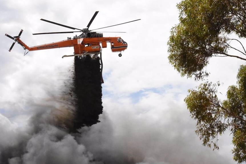 A helicopter drops black fire retardant on the blaze at Broadmeadows.