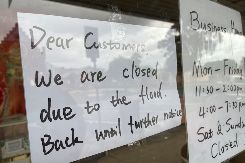 a sign on a window that says "we are closed due to the flood"
