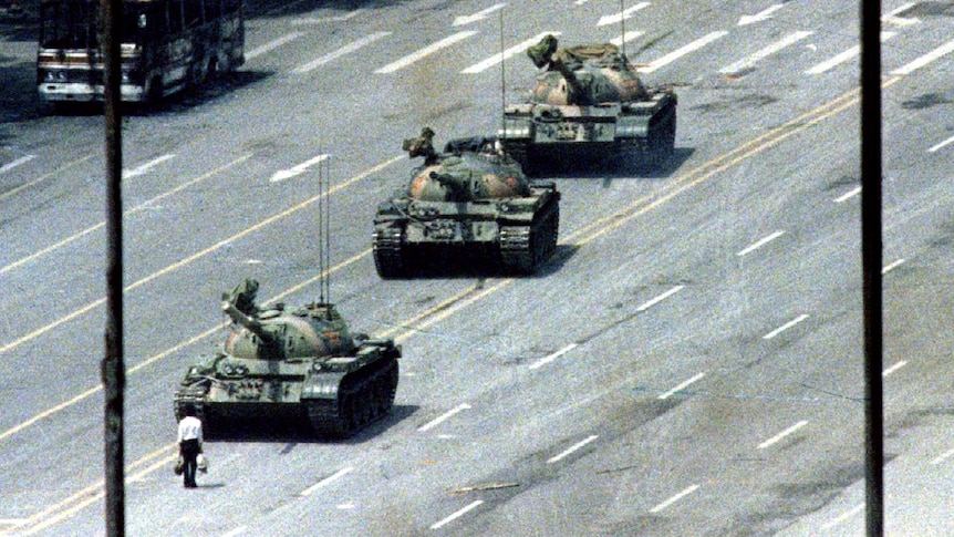 Un hombre se para frente a una fila de tanques.