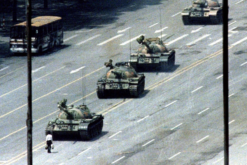 A man stands in front of a row of tanks