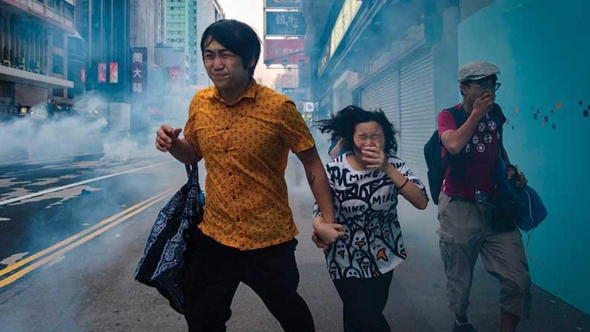 Protesters and bystanders on Nathan Road move through tear gas fired by the police during a pro-democracy march in Hong Kong.