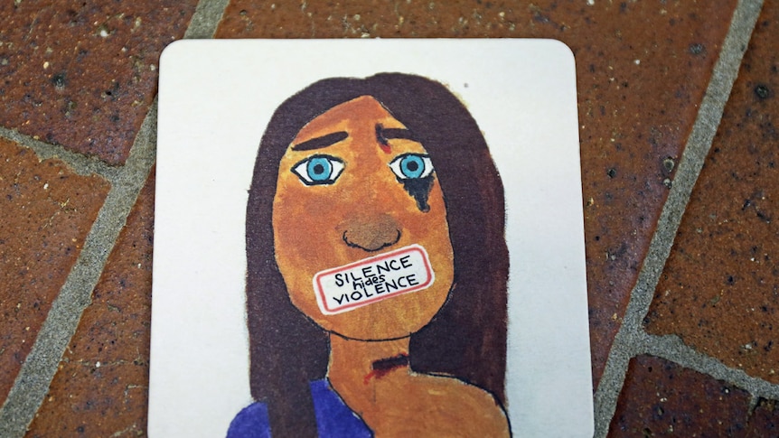 'Silence hides violence' message taped across a drawing of a woman's face