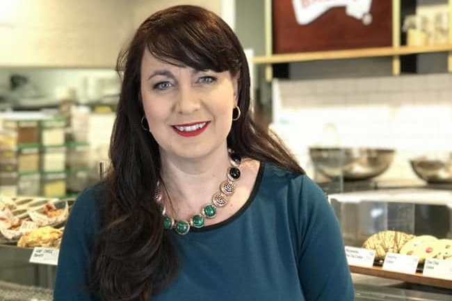 A woman poses for a photograph while standing in front of a food outlet