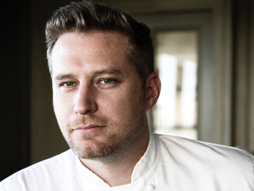 A man with fair hair wearing a white chef unifrom