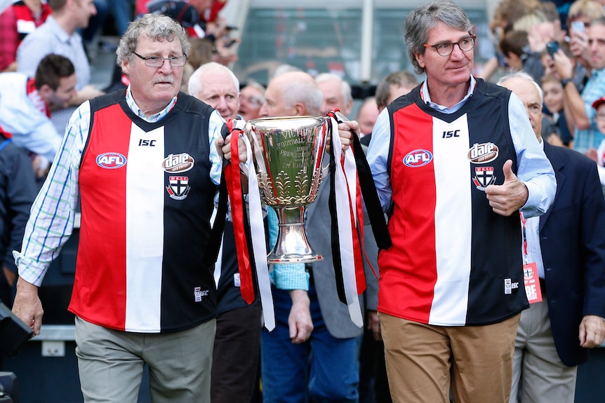 Kevin Neale and Barry Breen bring out the 1966 VFL premiership cup onto the MCG in 2016.