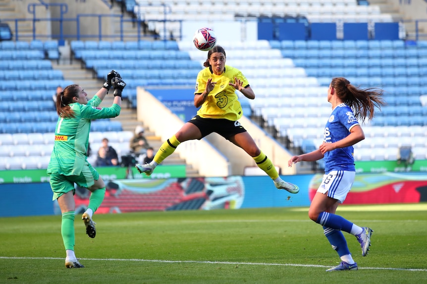 Sam Kerr is pictured heading a ball mid-air with Leicester City's goalkeeper to the left