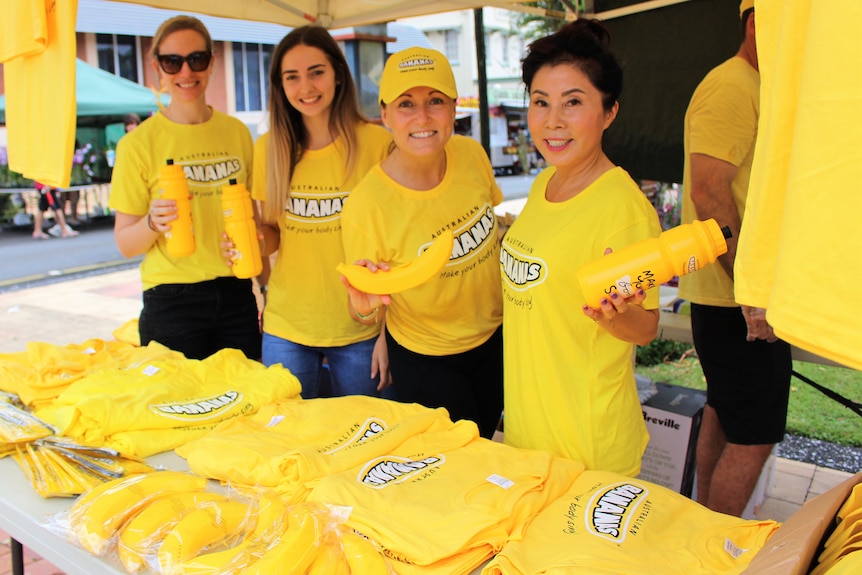 People dress in yellow t-shirts holding banana marketing products
