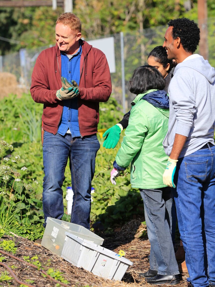 Dr Williams stands with students in a vegetable garden.