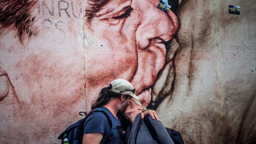 Kathrin and her husband in front of the famous mural painting of the kiss, imitating the kiss