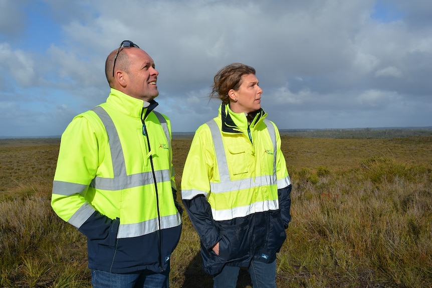 Two people from a renewable energy company standing in an open field which is the proposed site for a new wind farm.