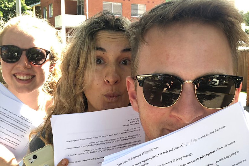 Three people holding up letters and posing for the camera.