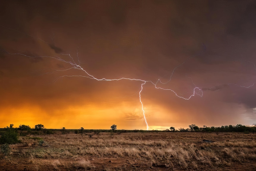 a lightning strike hitting the ground against a gloomy dark sunset