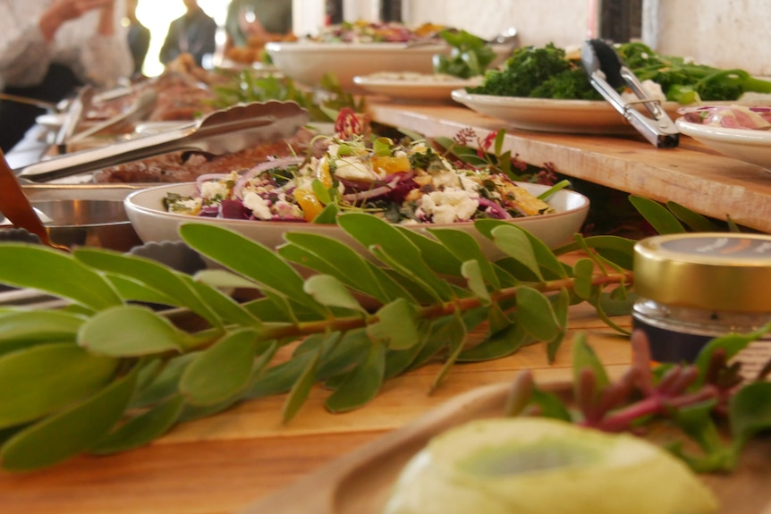 Salt bush in a salad on a table with many plates on display.