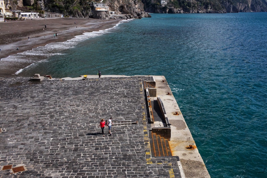 A couple walk along a dock on Italy's Amalfi Coast.