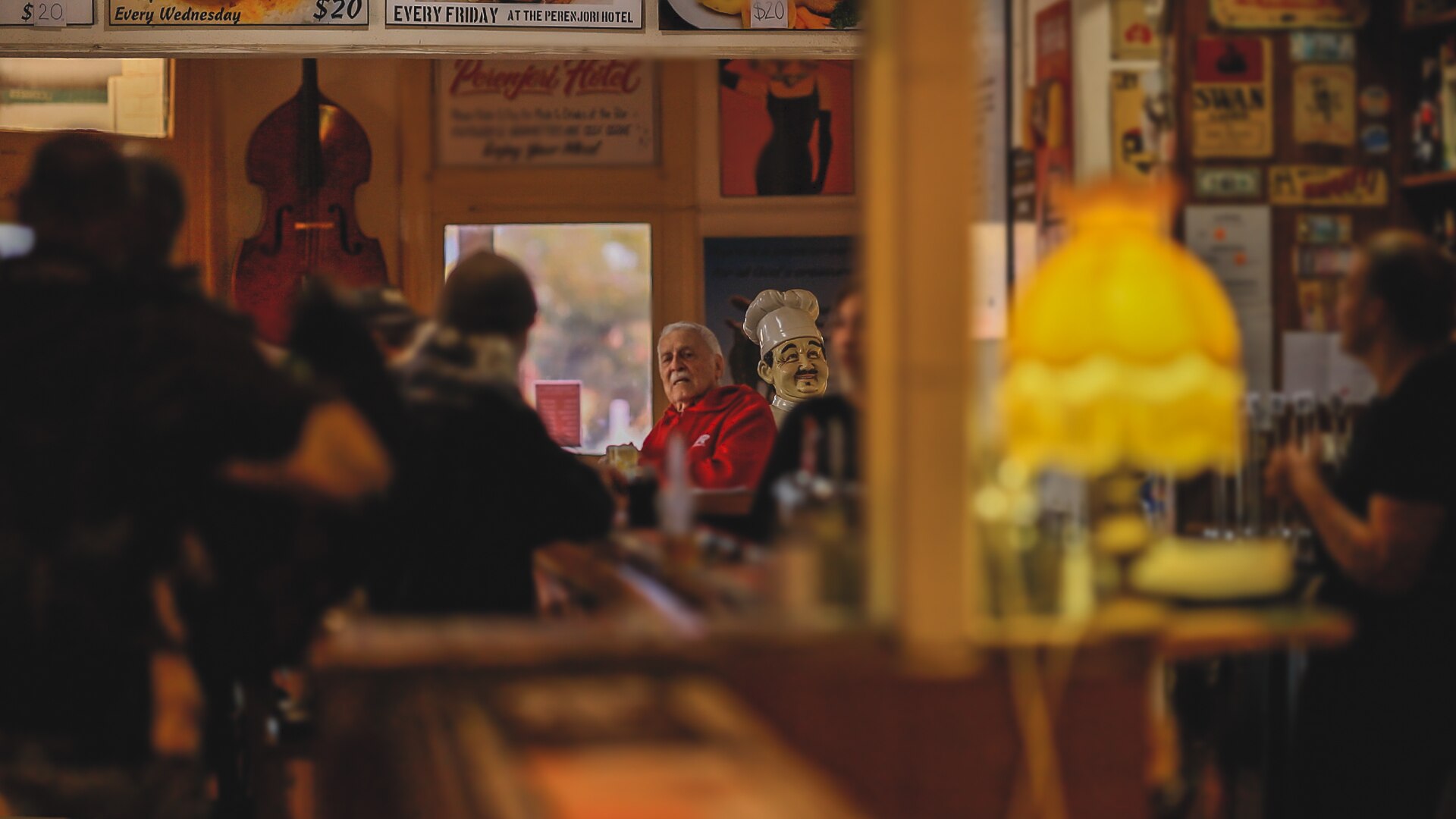 Jim Pohl sits at the end of the bar framed by customers