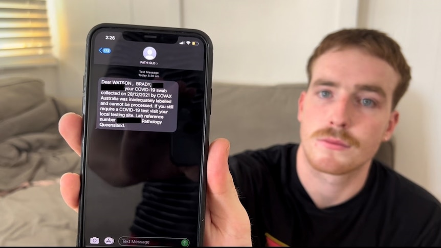 Brady Watson holds up a mobile phone showing a message from a COVID-19 testing clinic.