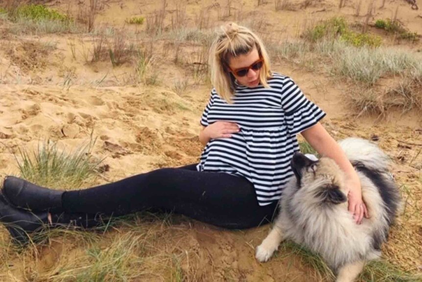 Grace Jennings-Edquist, pregnant on a beach and pictured with her dog