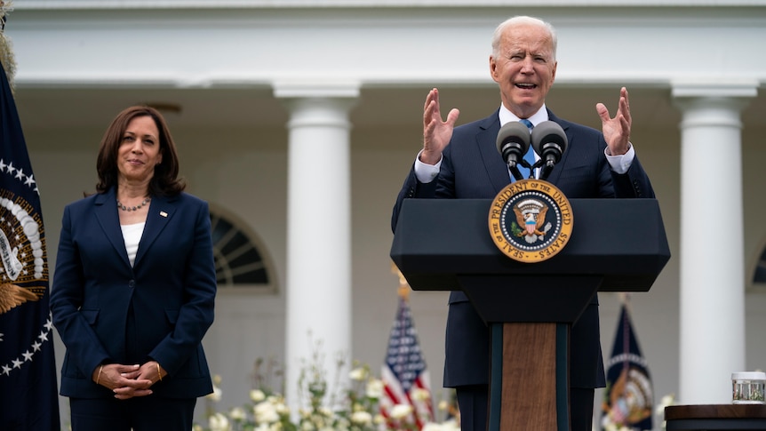 US Vice President Kamala Harris listens as President Joe Biden speaks at a podium in the Rose Garden of the White House