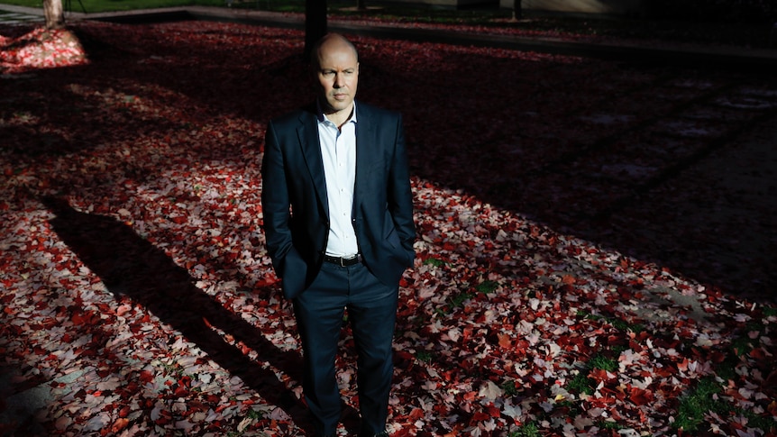 Treasurer Josh Frydenberg stands in a courtyard at Parliament House, looking serious.