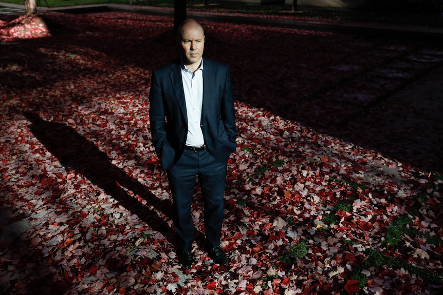 Treasurer Josh Frydenberg stands in a courtyard at Parliament House, looking serious.