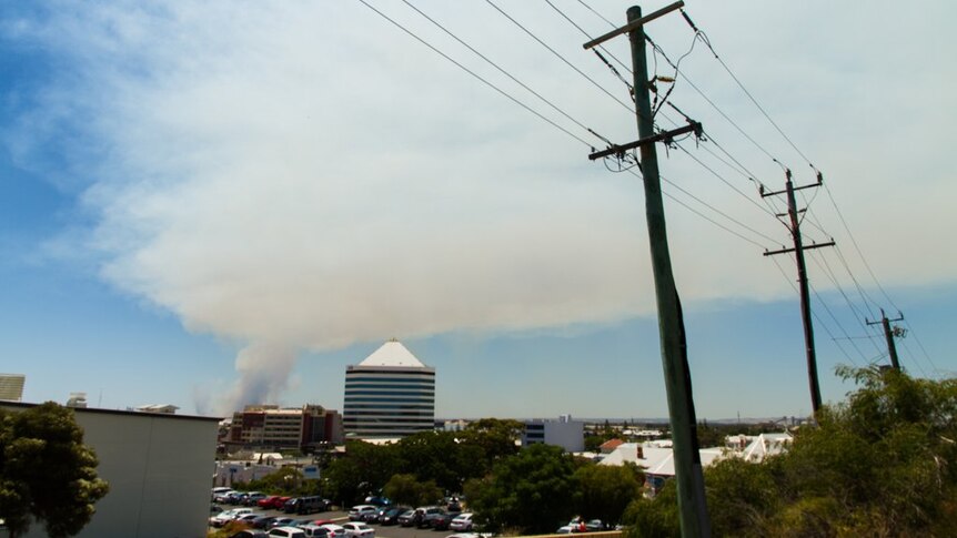 Smoke from a bushfire burning at Uduc drifts over buildings and powerlines in Bunbury.