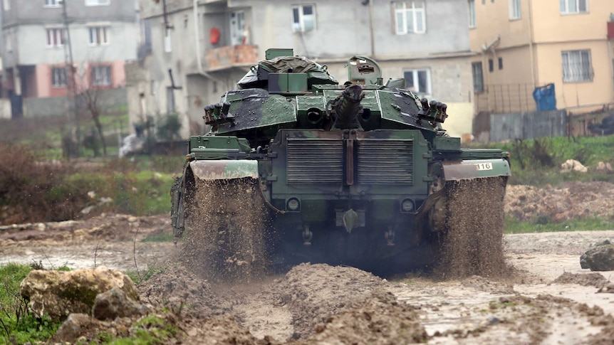 A Turkish army tank moves through thick mud toward the Syrian border, in Reyhanlı, Turkey