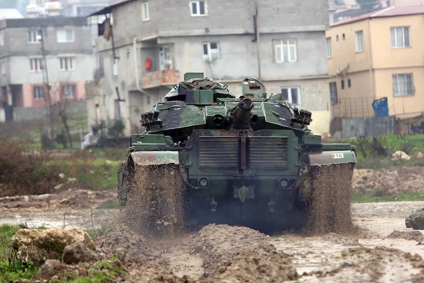 A Turkish army tank moves through thick mud toward the Syrian border, in Reyhanlı, Turkey