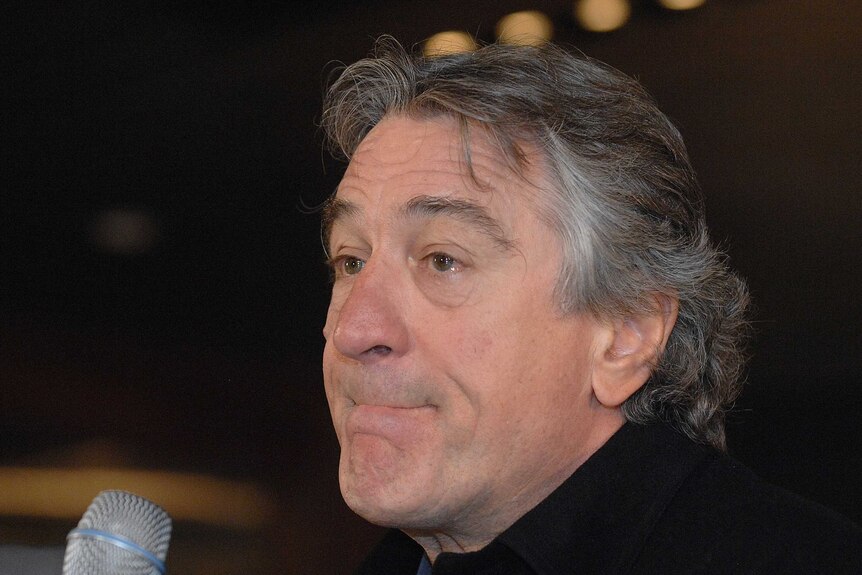 Close up of Robert de Niro in front of a microphone.