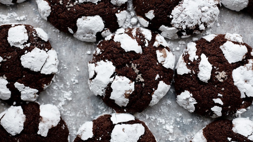 Close-up of a batch of dark chocolate crinkle cookies, a delicious dessert recipe.