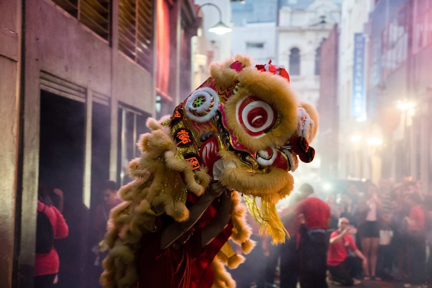 high resolution image of yellow and red chinese lion costume in front of chinatown background