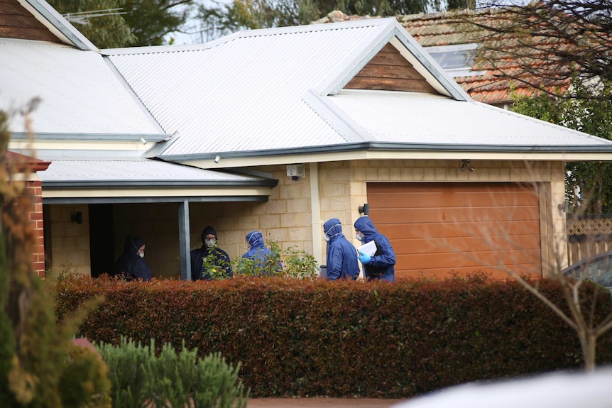 Five forensic officers wearing masks and protective suits enter the brick and tin-roofed home.