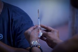 A close up shot of a syringe prior to a drug user injecting.