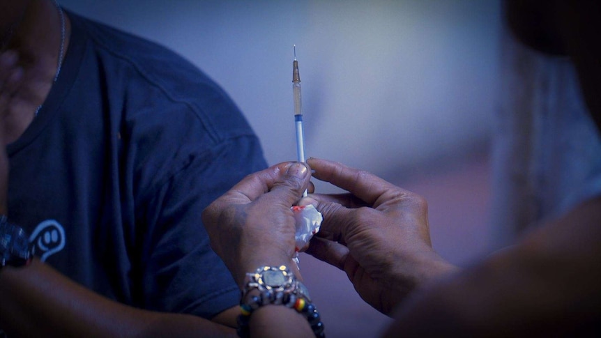 A close up shot of a syringe prior to a drug user injecting.