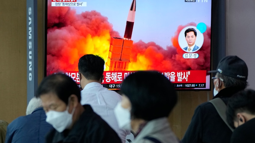 Photo shows people watching a television with a missile shooting in the sky in South Korea 
