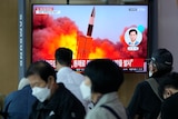 Photo shows people watching a television with a missile shooting in the sky in South Korea 