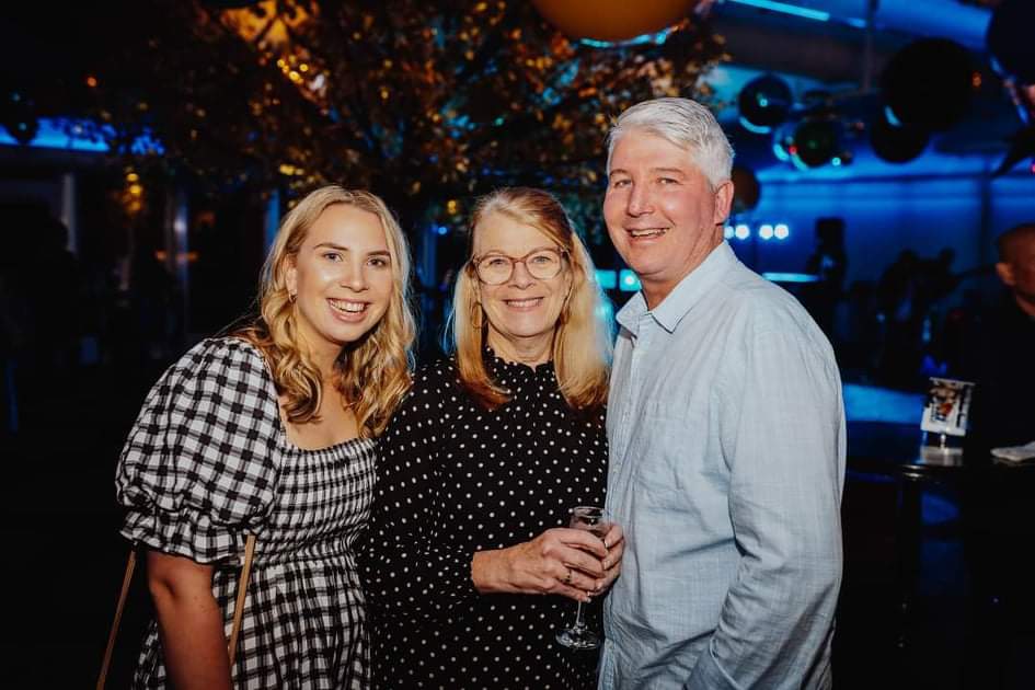 A young girl hugs an older couple.