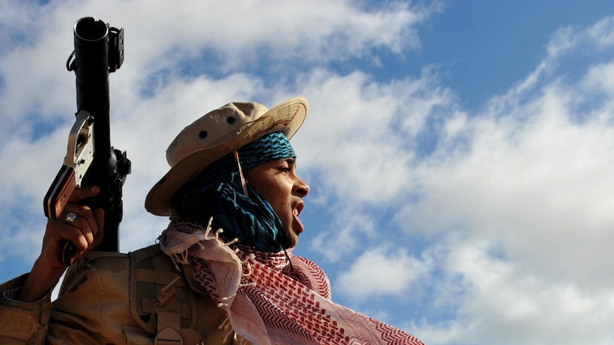 A Libyan rebel holds a rocket propelled grenade launcher after spotting a fighter jet flying overhead near Ras Lanuf