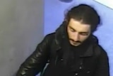 A man appears in CCTV vision wearing dark clothing and tracksuit pants.