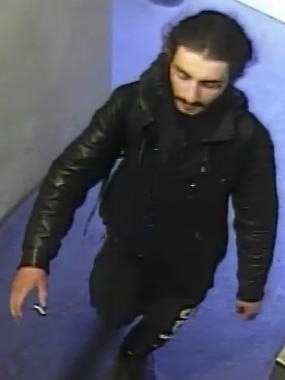 A man appears in CCTV vision wearing dark clothing and tracksuit pants.
