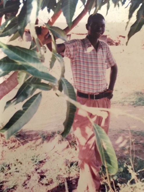 Louis Kristopher standing under a tree at a refugee camp in Uganda.