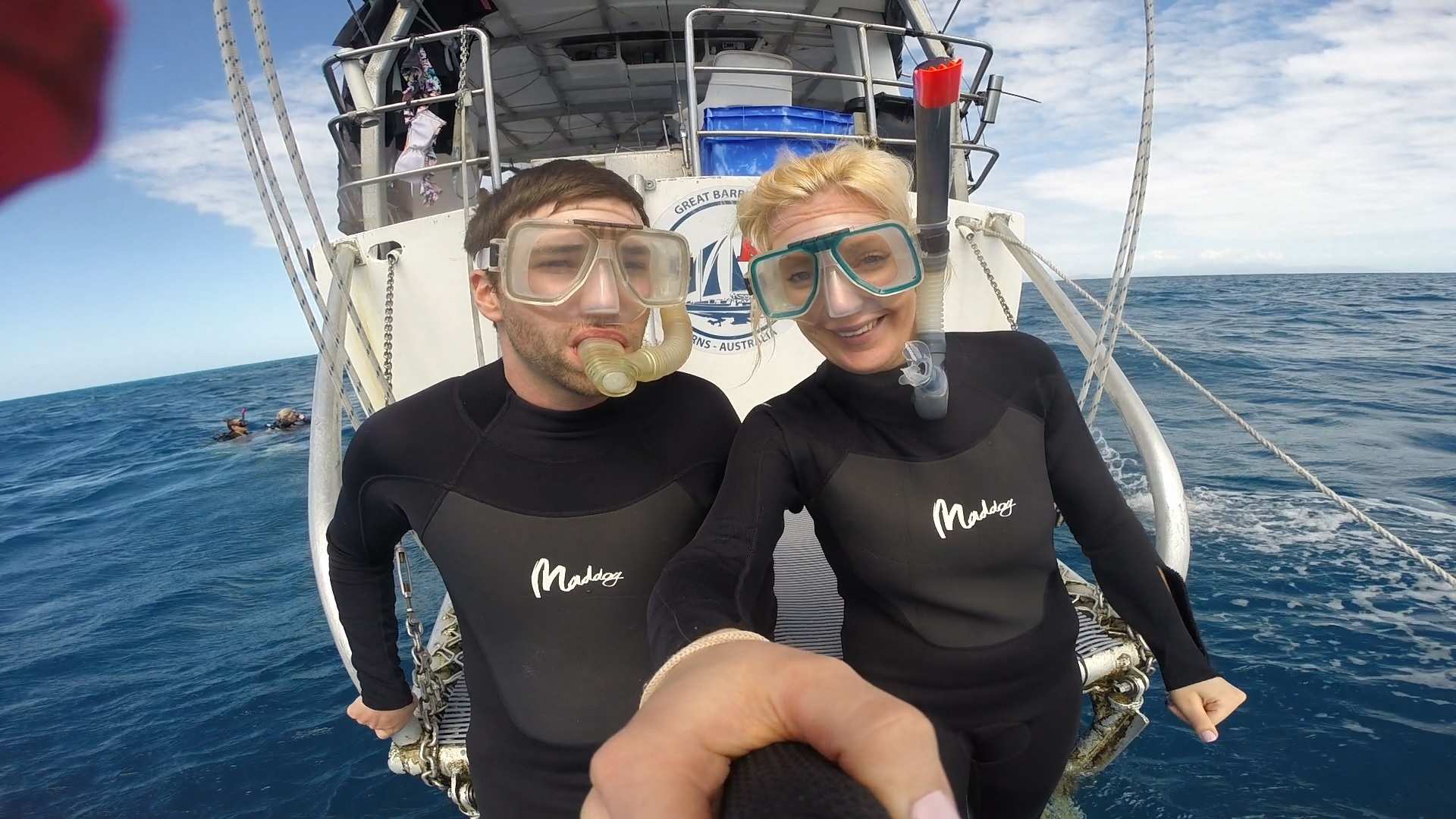A man and woman smiles for a photo on a boat in the ocean
