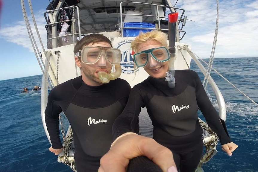 A man and woman smiles for a photo on a boat in the ocean