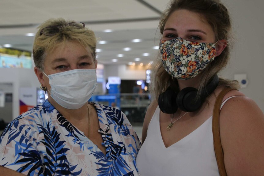 Two women wearing face masks look at the camera.