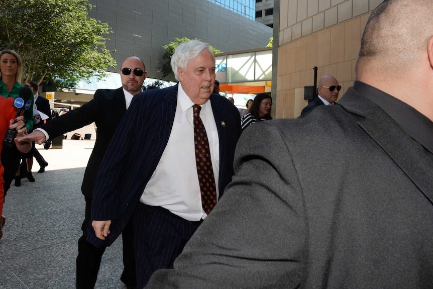 Businessman Clive Palmer, flanked by security guards.