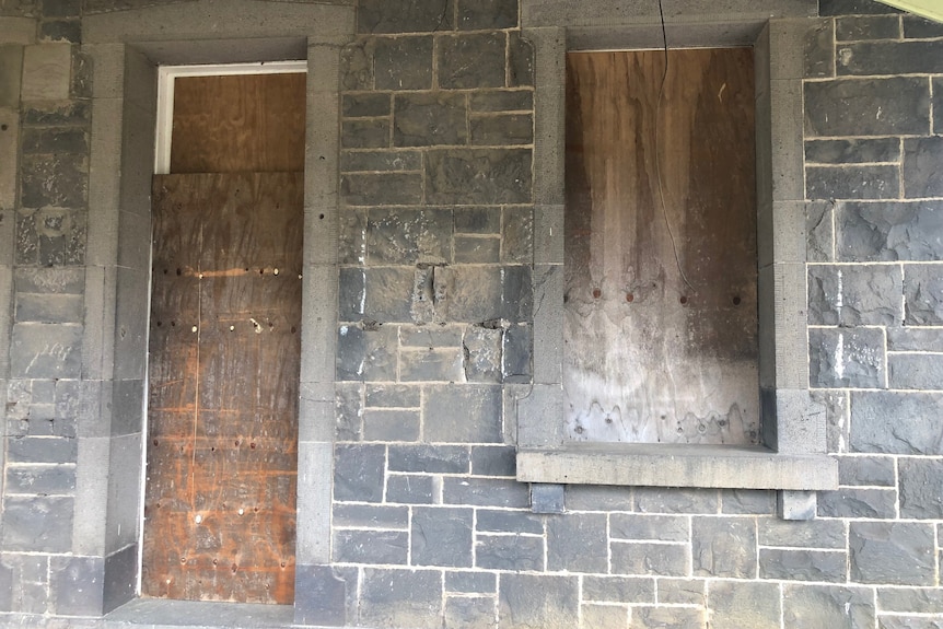 Boarded up window and door on an old blue stone building