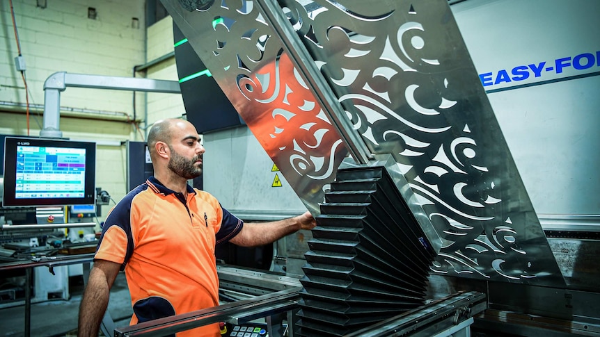 A man working on a steel fabrication sheet in a factory